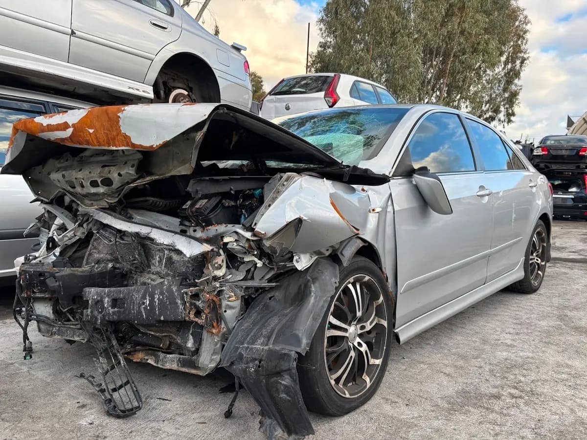 Severely collision-damaged silver sedan collected by iCar Removals from a Perth accident car removal, awaiting dismantling at the yard