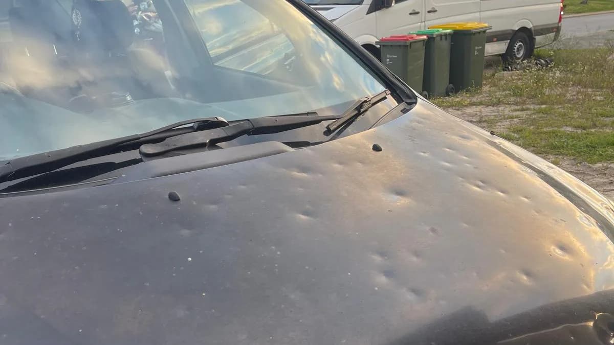 Hail damaged black Toyota with hundreds of dents across the bonnet, photographed in a Perth suburb with the iCar Removals van on site