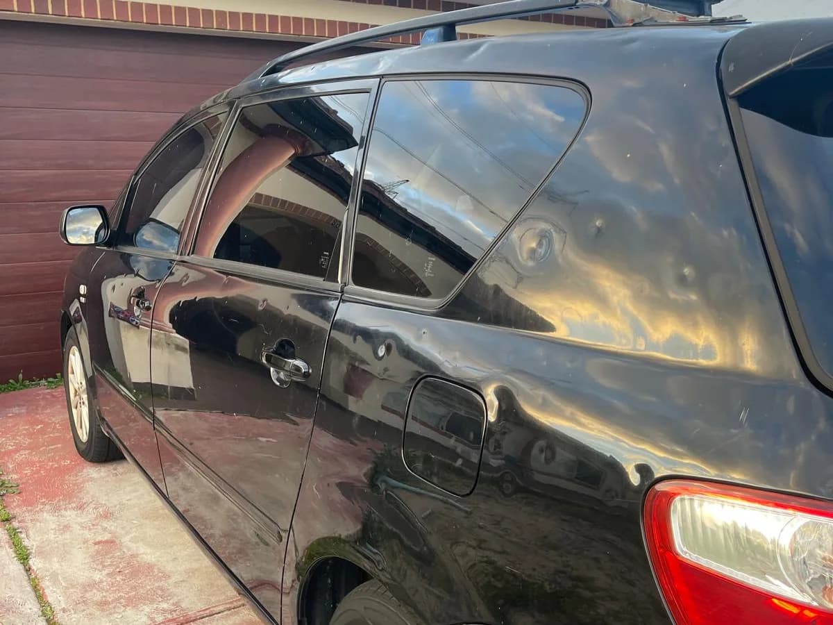 Full side profile of a hail damaged Toyota people mover on collection day in Bennett Springs Perth