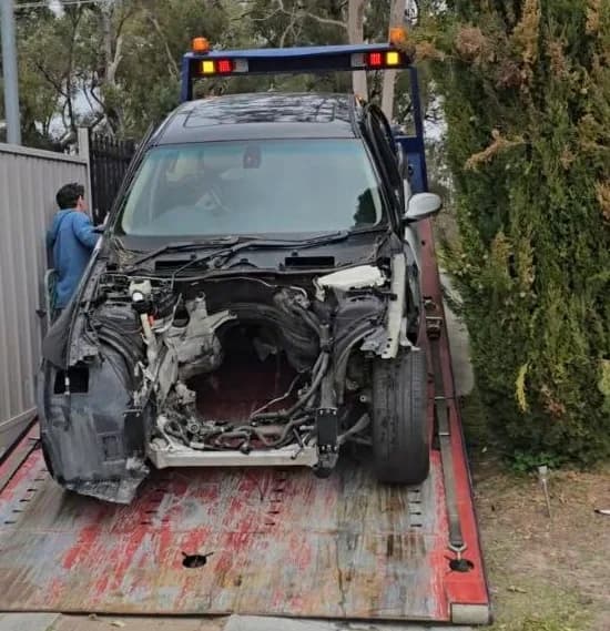 Severely front-end damaged car being loaded onto an iCar Removals tilt tray truck in Perth