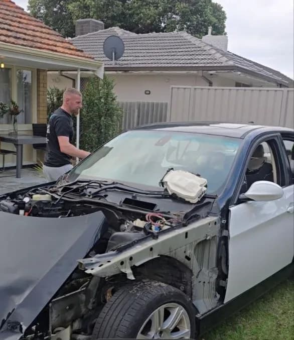 White sedan with severe front-end accident damage awaiting collection by iCar Removals in a Perth backyard