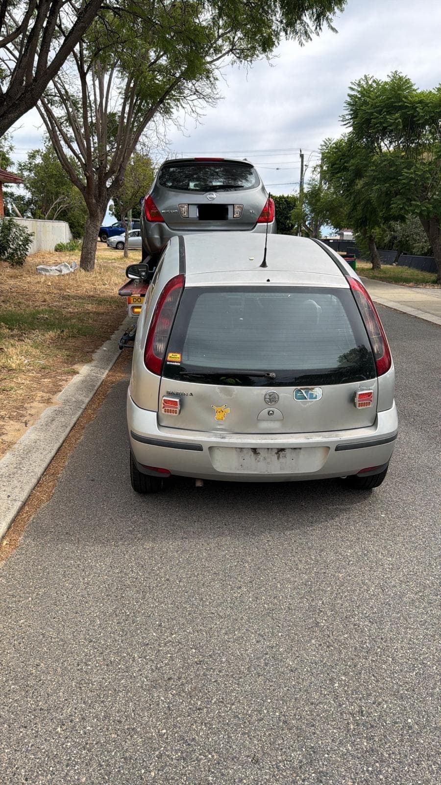 Two non-running cars loaded on an iCar Removals trailer during a car removal in a Perth street